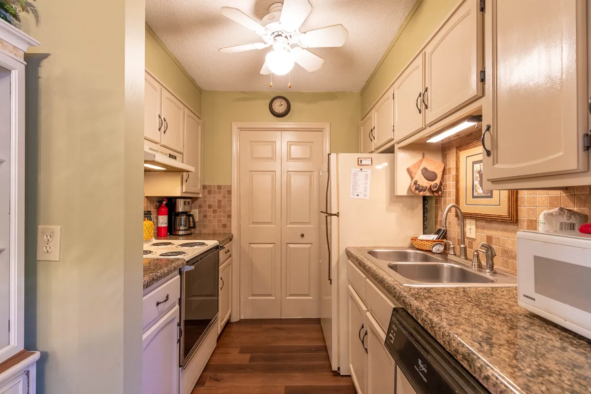 A cozy, welcoming kitchen featuring granite countertops, modern appliances, and touches like a ceiling fan, clock, and decorative artwork. The space is set up for meal prep, with room for family gatherings and celebrations, evoking the feel of home-cooked meals shared together.